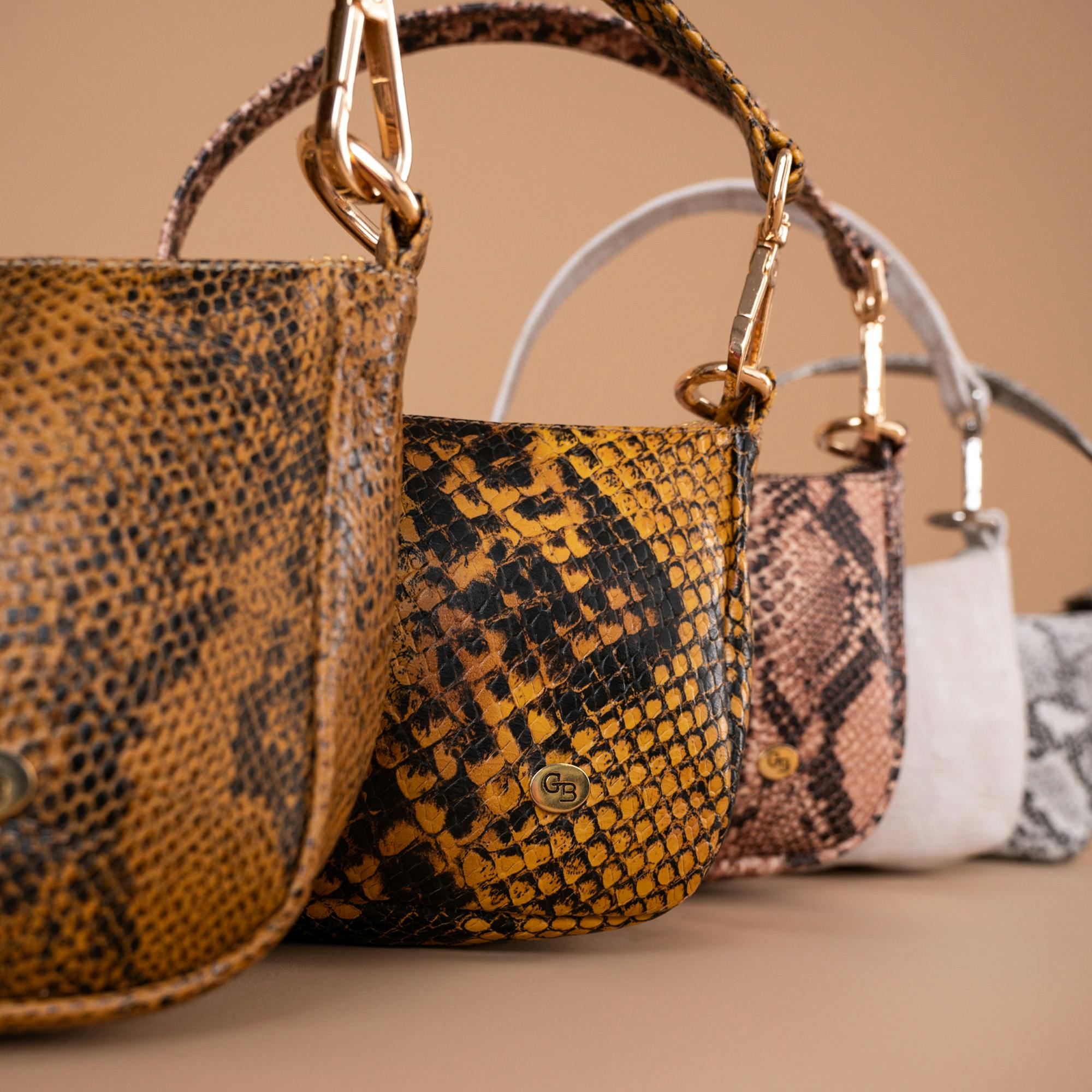 Elegant snake print leather handbags arranged in a stylish line. Perfect for fashion and luxury themes.